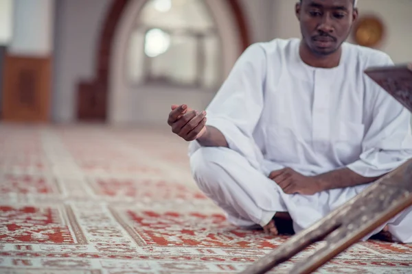 Schwarzafrikanischer muslimischer Mann betet in der Moschee mit offenem heiligen Koranbuch — Stockfoto