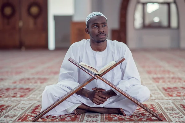 Μαύρο αφρικανική μουσουλμανική άνθρωπος είναι προσεύχεται για το τζαμί με ανοιχτό ιερό βιβλίο του Κορανίου — Φωτογραφία Αρχείου