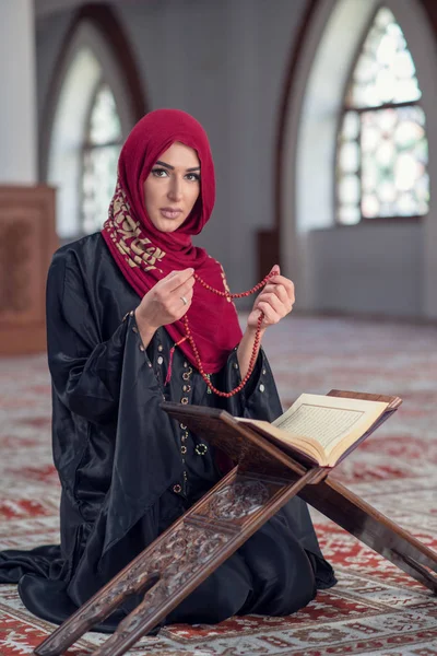 Молодая мусульманка молится с четками в мечети — стоковое фото