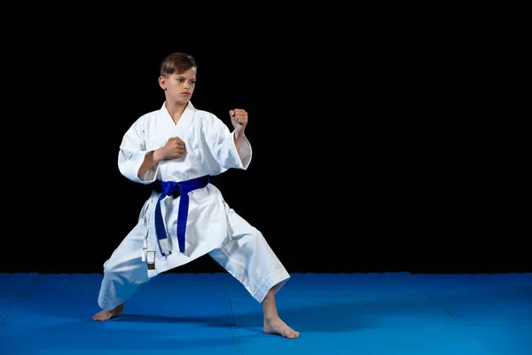 Pre-adolescente chico haciendo karate en un fondo negro — Foto de Stock