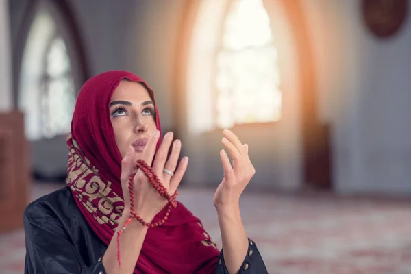 Молодая мусульманка молится с четками в мечети — стоковое фото