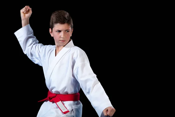 Jonge jongen, gekleed in een wit karate kimono met rode riem. — Stockfoto