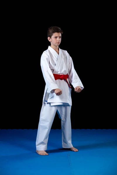 Jeune garçon vêtu d'un kimono de karaté blanc avec ceinture rouge . — Photo