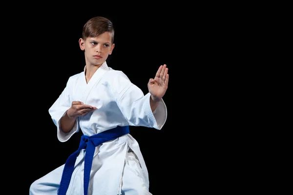 Pre-teen jongen doen karate op een zwarte achtergrond — Stockfoto