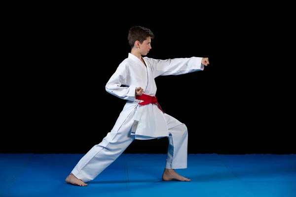 Niño vestido con un kimono de karate blanco con cinturón rojo . — Foto de Stock