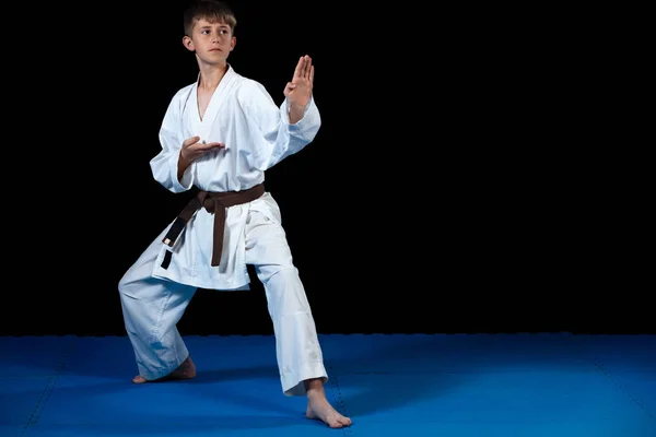 Joven niño entrenamiento karate en negro fondo — Foto de Stock