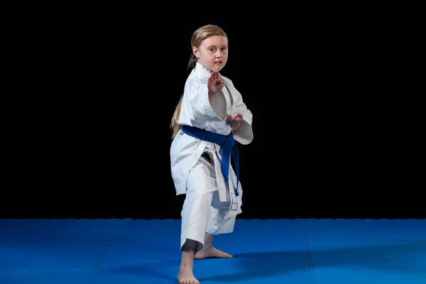 Dulce niña en las artes marciales práctica como karate niño solo aislado en negro fondo — Foto de Stock