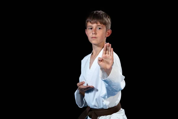 Ung pojke utbildning karate på svart bakgrund — Stockfoto