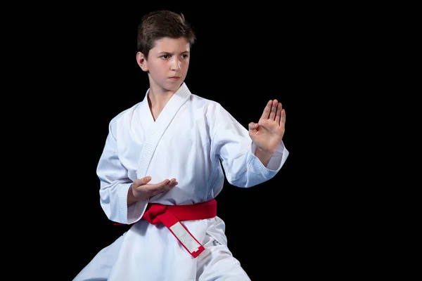 Niño vestido con un kimono de karate blanco con cinturón rojo . — Foto de Stock