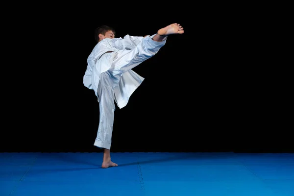 Joven niño entrenamiento karate en negro fondo — Foto de Stock
