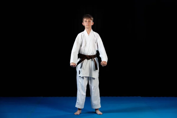 Joven niño entrenamiento karate en negro fondo — Foto de Stock