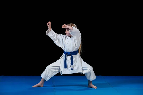 sweet little girl in martial arts practice like karate kid alone isolated on black background