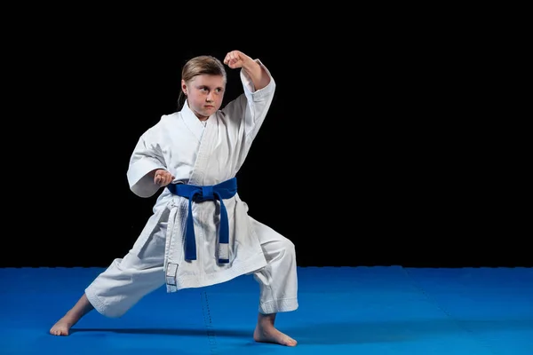 Doce menina no artes marciais prática como karatê miúdo sozinho isolado no preto fundo — Fotografia de Stock