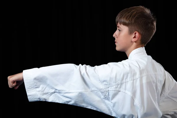 Joven niño entrenamiento karate en negro fondo — Foto de Stock