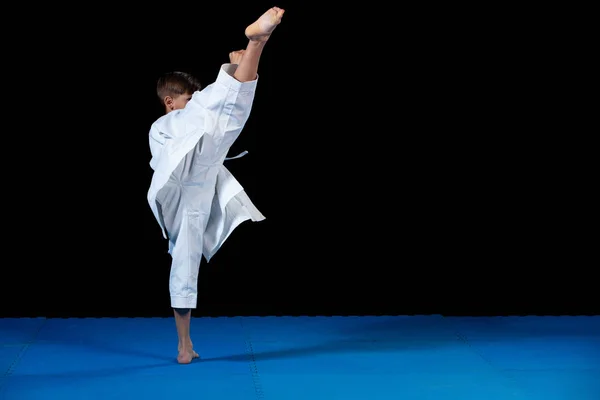 Pre-adolescente chico haciendo karate en un fondo negro — Foto de Stock