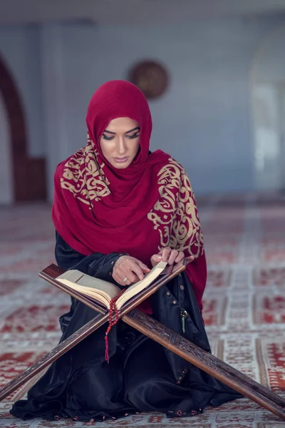 Mujer musulmana leyendo el Corán o el Corán vestida con un vestido tradicional en la mezquita — Foto de Stock