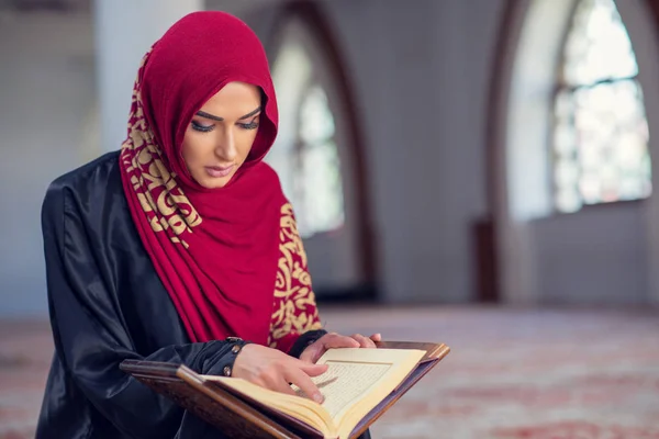 Mujer musulmana leyendo el Corán o el Corán vestida con un vestido tradicional en la mezquita — Foto de Stock