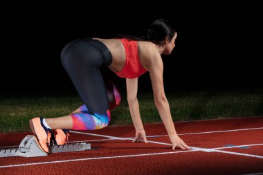 kadın atlet atletik yolda başlayan blok bırakarak. başlangıç tarihinde stadyum reflektör patlayan