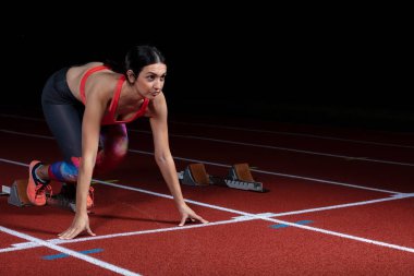 kadın atlet atletik yolda başlayan blok bırakarak. başlangıç tarihinde stadyum reflektör patlayan