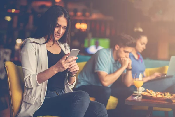 Young woman using mobile phone in front of her team in startup office — Stock Photo, Image