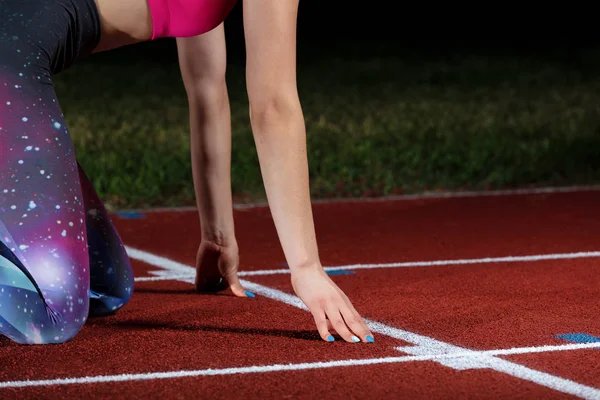 Woman sprinter leaving starting blocks on the athletic track. exploding start on stadium with reflectors — Stock Photo, Image