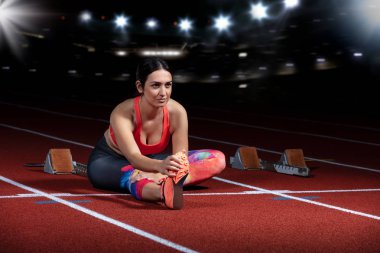 genç atletik kadının esneklik egzersizleri yapması. parça Stadyumu, otururken bacak Germe gece reflektör