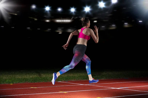 Žena sprinter opuštění startovací bloky na atletické dráze. explodující start na stadionu s reflektory — Stock fotografie