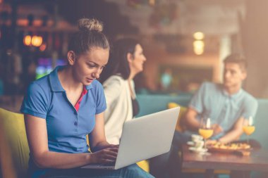 Genç kız öğrenci kafede dizüstü bilgisayar kullanıyor