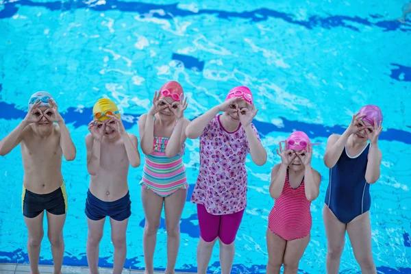 Счастливая детская группа в бассейне, где учат плавать — стоковое фото