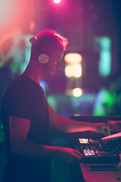 Club, disco DJ tocando y mezclando música para multitud de gente feliz. Vida nocturna, luces de concierto, bengalas. — Foto de Stock