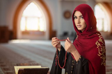 Genç Müslüman kadının camide Kur'an-ı Kerim ile dua