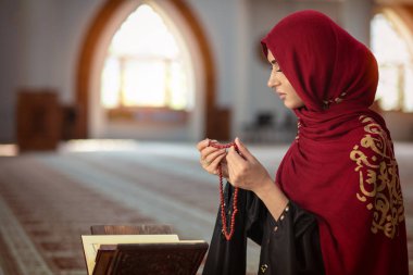Genç Müslüman kadının camide Kur'an-ı Kerim ile dua