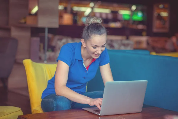 Переможець дівчина-еуфорик дивиться ноутбук у кав'ярні в синій сорочці — стокове фото