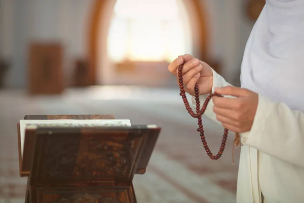 Jovem mulher muçulmana orando na mesquita com o Alcorão — Fotografia de Stock