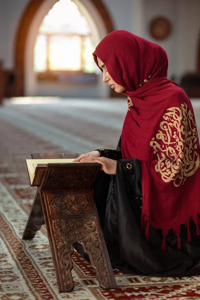 Jovem mulher muçulmana orando na mesquita com o Alcorão — Fotografia de Stock