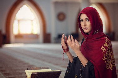 Genç Müslüman kadının camide Kur'an-ı Kerim ile dua