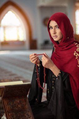 Genç Müslüman kadının camide Kur'an-ı Kerim ile dua