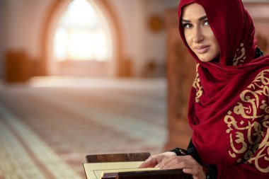 Genç Müslüman kadının camide Kur'an-ı Kerim ile dua