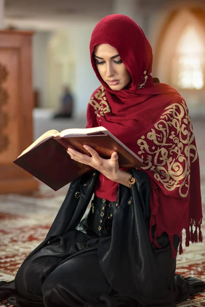 Jovem mulher muçulmana orando na mesquita com o Alcorão — Fotografia de Stock