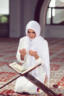 Genç Müslüman kadının camide Kur'an-ı Kerim ile dua