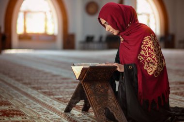 Genç Müslüman kadının camide Kur'an-ı Kerim ile dua