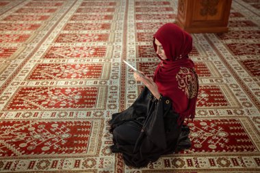 Genç Müslüman kadının camide kuran tablet ile dua