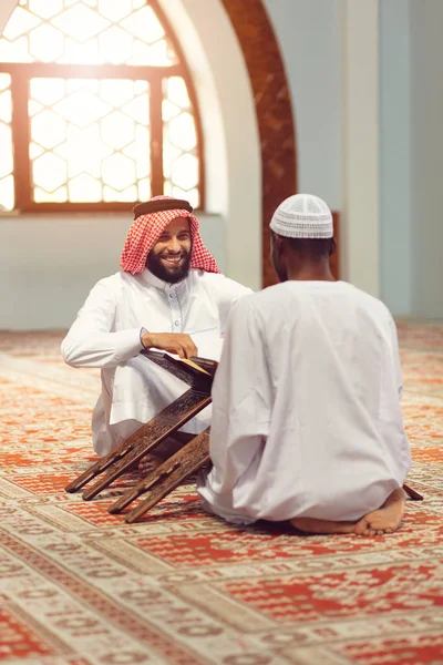 Homens muçulmanos rezando com livros sagrados na mesquita — Fotografia de Stock