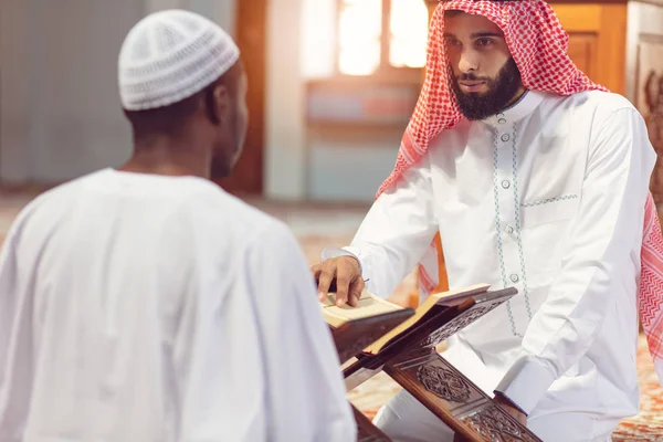 Homens muçulmanos rezando com livros sagrados na mesquita — Fotografia de Stock