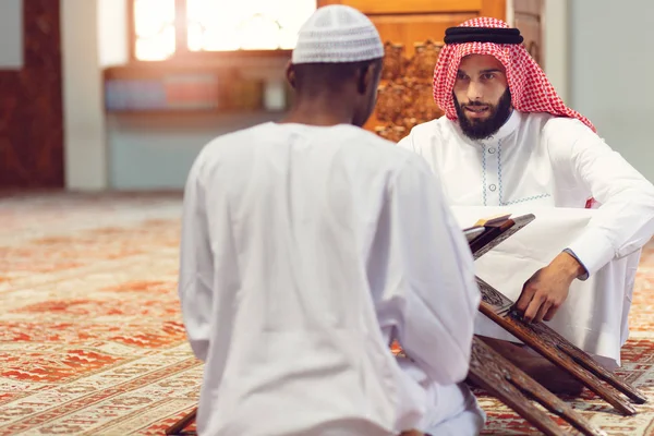 Homens muçulmanos rezando com livros sagrados na mesquita — Fotografia de Stock