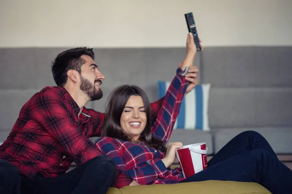 Pareja luchando por el control remoto mientras ve la televisión en casa — Foto de Stock