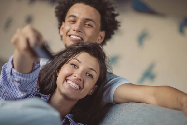 Mladý černý pár odpočinku na gauči a usmívá se na kameru — Stock fotografie