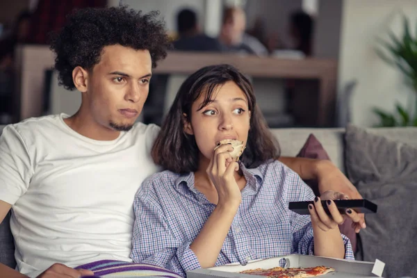 Casal feliz assistindo TV enquanto come pizza. Profundidade de campo rasa, foco no homem — Fotografia de Stock