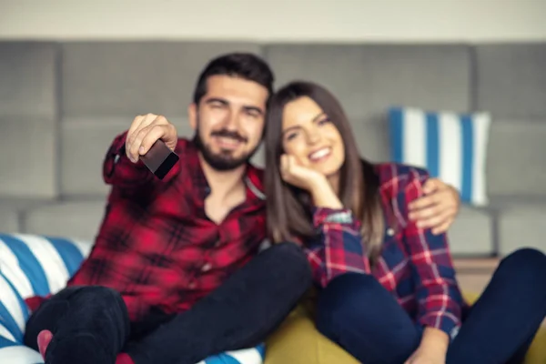 Casal lutando por controle remoto enquanto assiste TV em casa — Fotografia de Stock