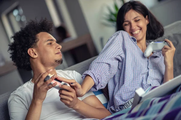 Imagem de jovem casal amoroso na cozinha em casa dentro de casa. Comer pizza e jogar jogos com console . — Fotografia de Stock